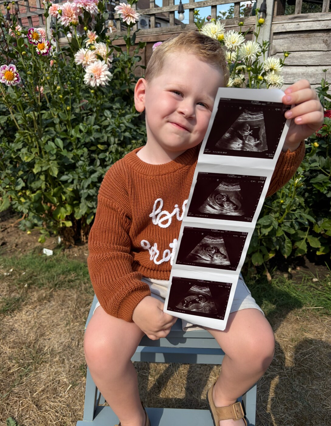 Ira proudly holding ultrasound scan photographs