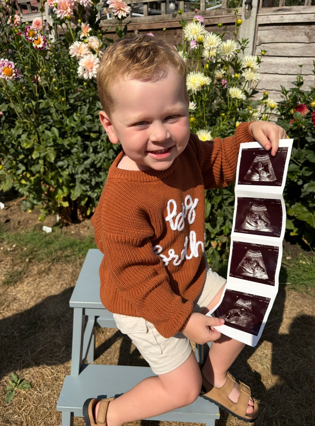 Ira smiling while holding ultrasound scan photographs